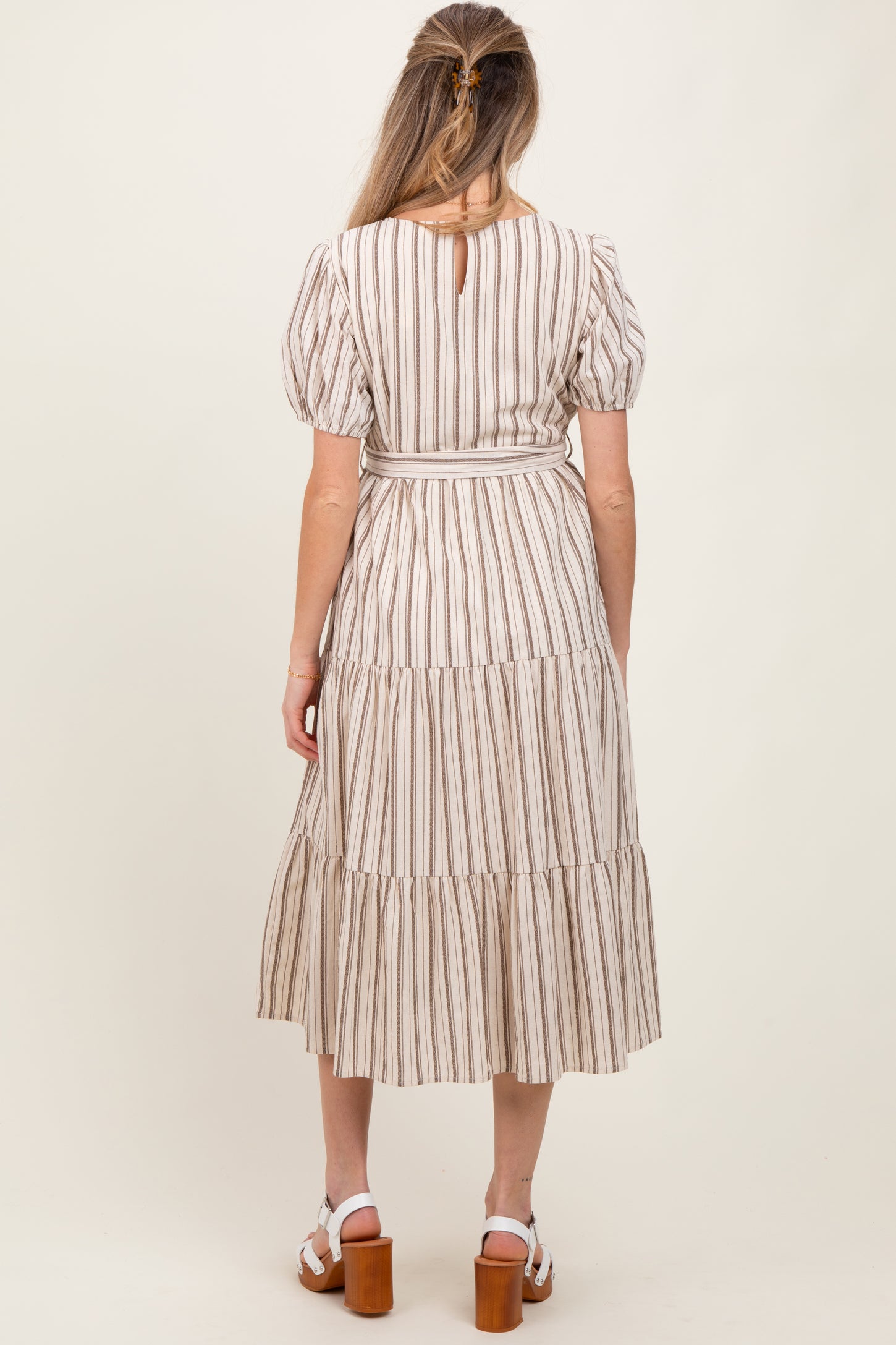 woman wearing a striped maternity maxi dress with puff sleeves and tiered skirt, showing a baby bump from the back