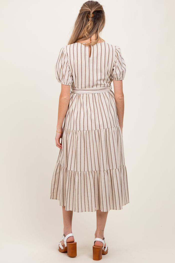 woman wearing a striped maternity maxi dress with puff sleeves and tiered skirt, showing a baby bump from the back