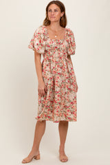 woman wearing a floral midi dress with puff sleeves and a cinched waist, standing on a neutral background