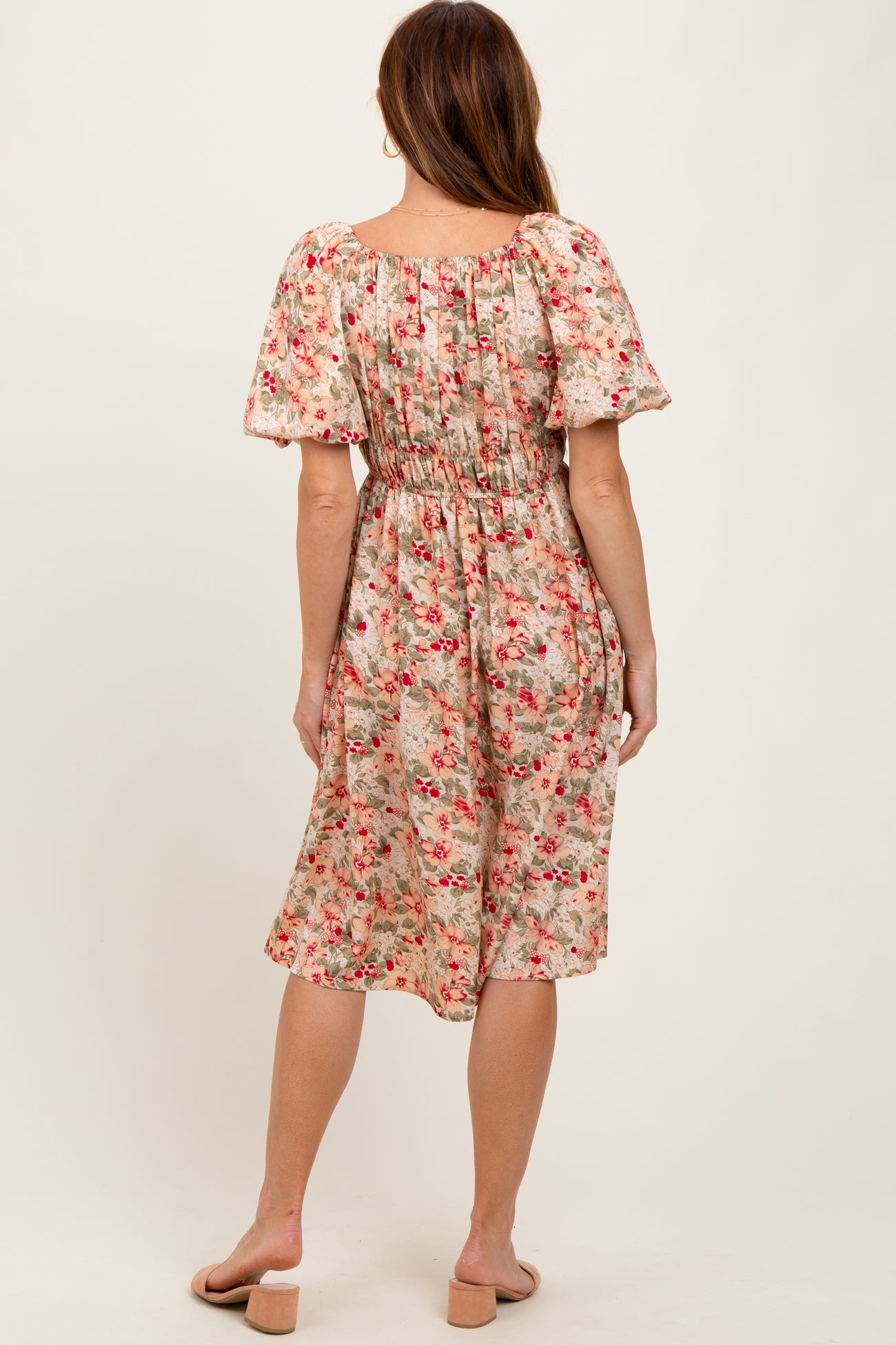 woman wearing a back view of a flowy floral midi dress with puff sleeves and an elasticated waist
