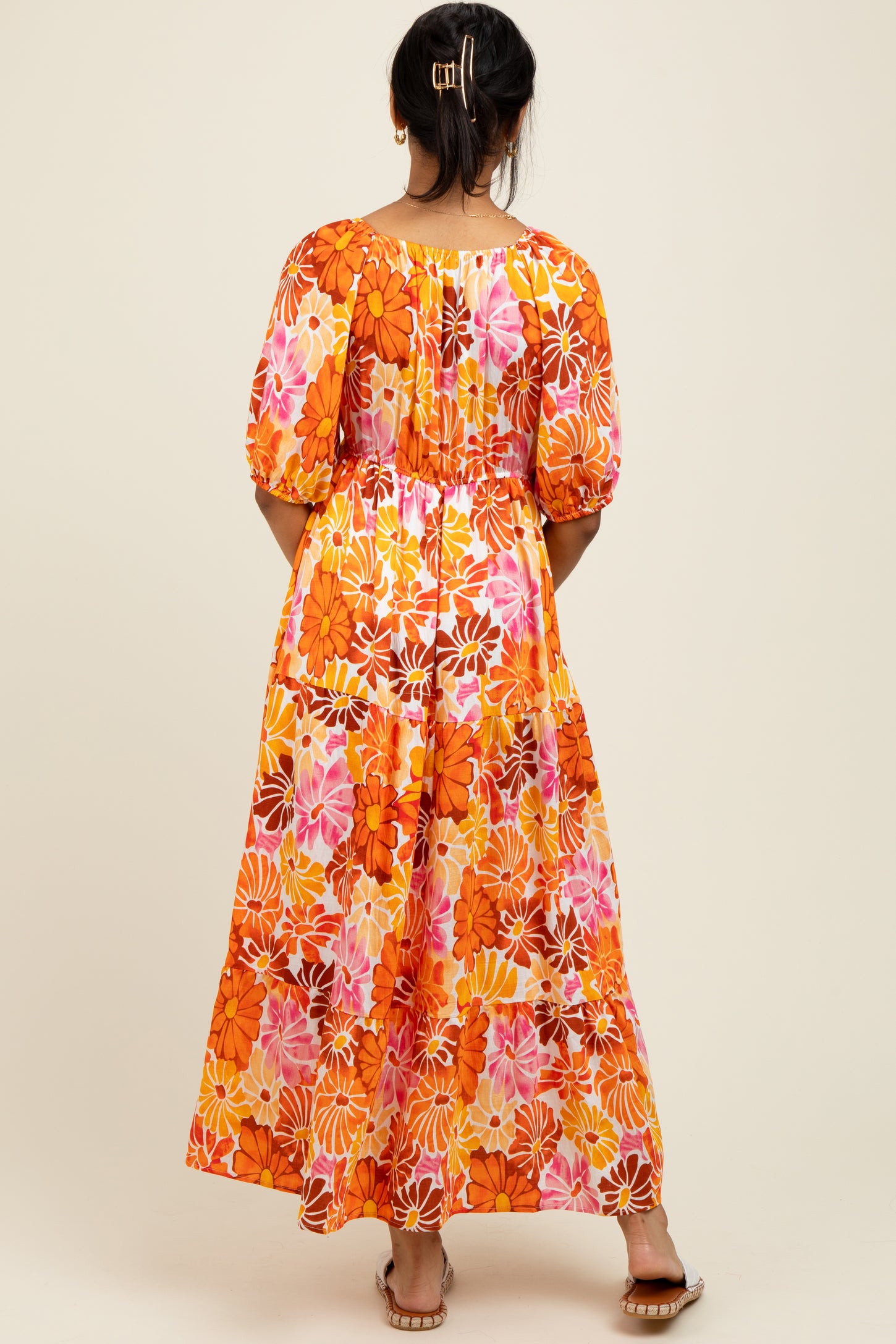 woman wearing a colorful floral maxi dress with puff sleeves and a cinched waist, shown from the back