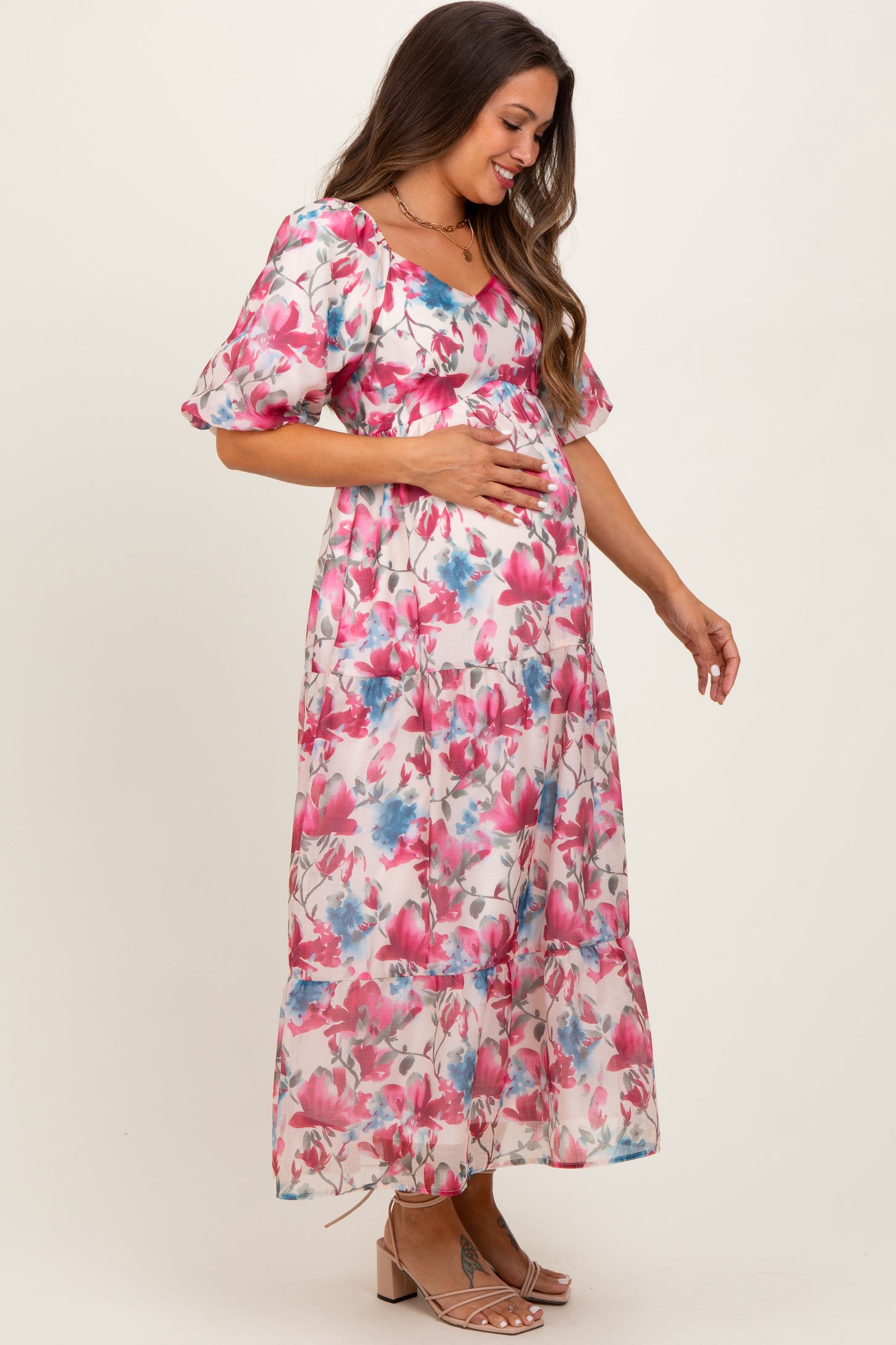 woman wearing a floral maternity maxi dress with short puff sleeves and holding her baby bump