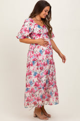 woman wearing a floral maternity maxi dress with short puff sleeves and holding her baby bump