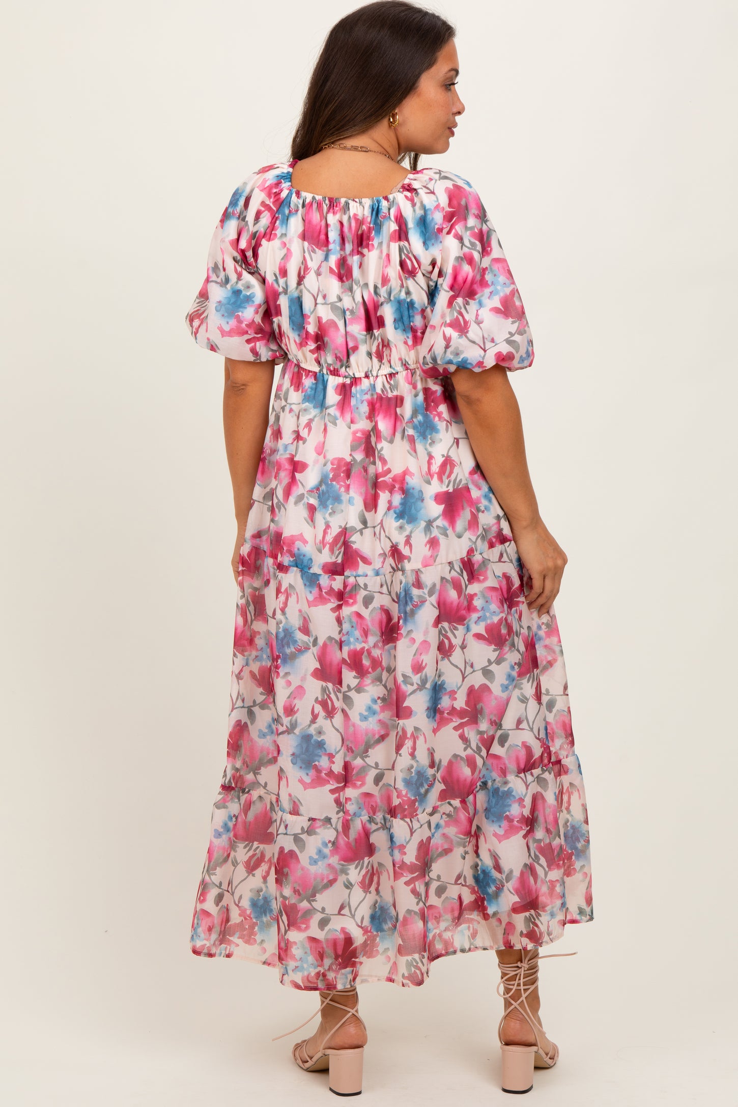 woman wearing a floral maternity maxi dress with puff sleeves and a cinched waist, showing a baby bump from the back