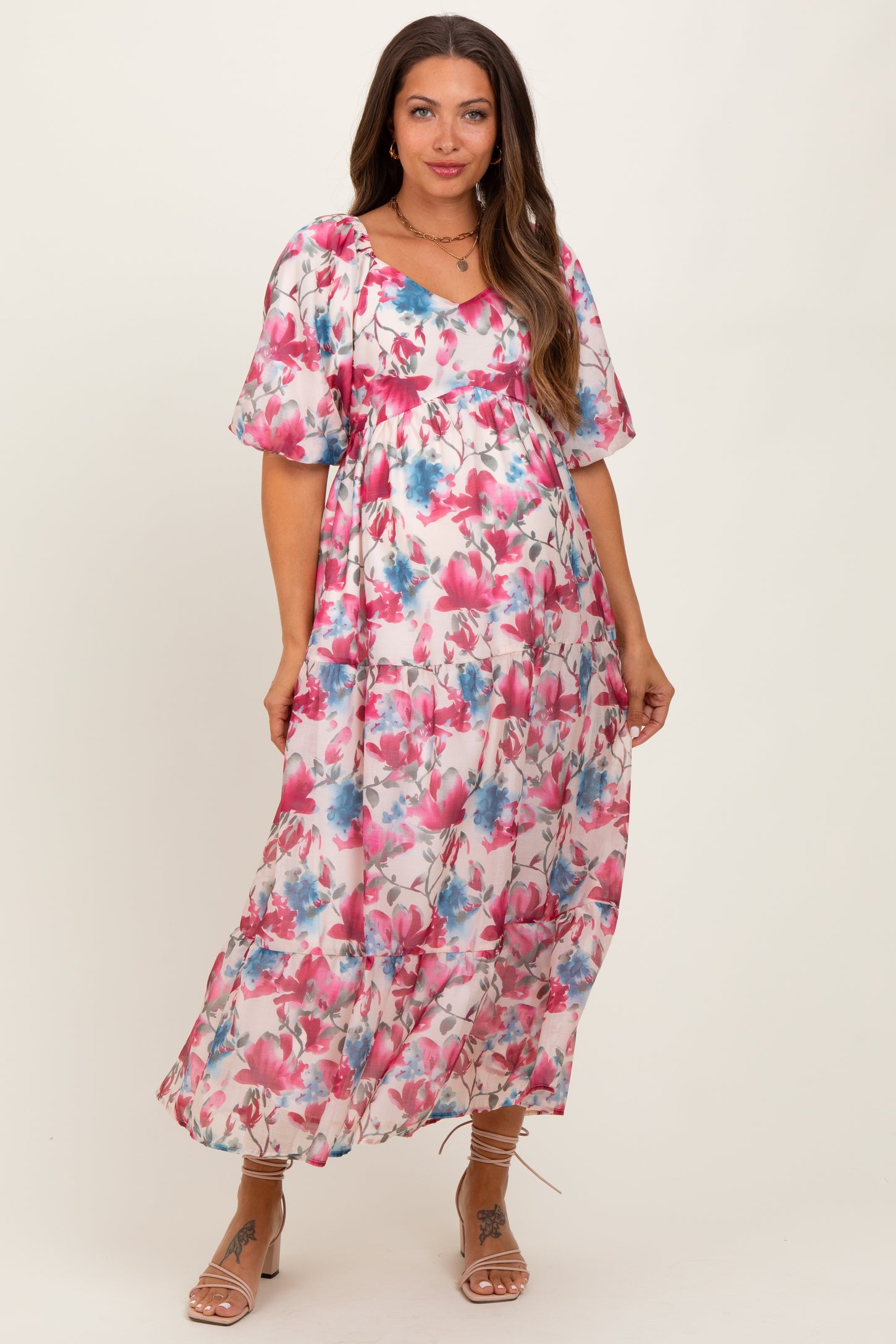 woman wearing a floral pink and blue maternity dress with short puff sleeves and a flowy silhouette, showing her baby bump