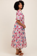 woman wearing a floral maxi dress with short puff sleeves in pink and blue tones, standing in profile