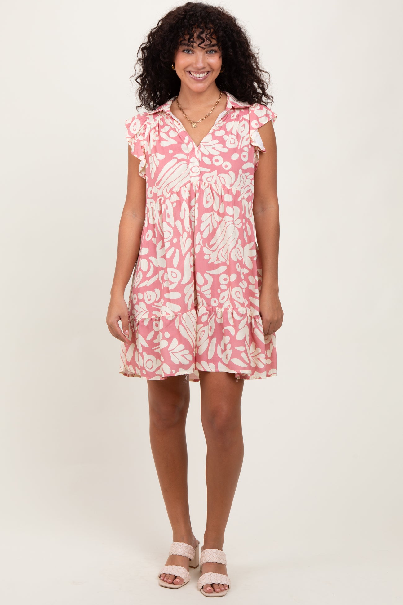 woman wearing a pink floral short sleeve dress with ruffle details and a button-down front