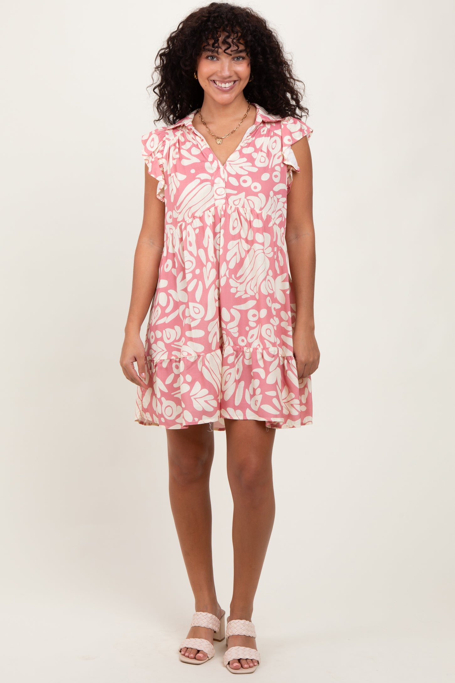 woman wearing a pink floral short sleeve dress with ruffle details and a button-down front