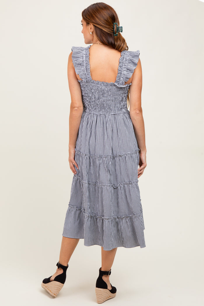 woman wearing a navy blue gingham tiered midi dress with ruffled sleeves and a smocked back