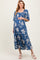 woman wearing a blue floral maternity dress with a smocked bodice and tiered skirt, holding her baby bump