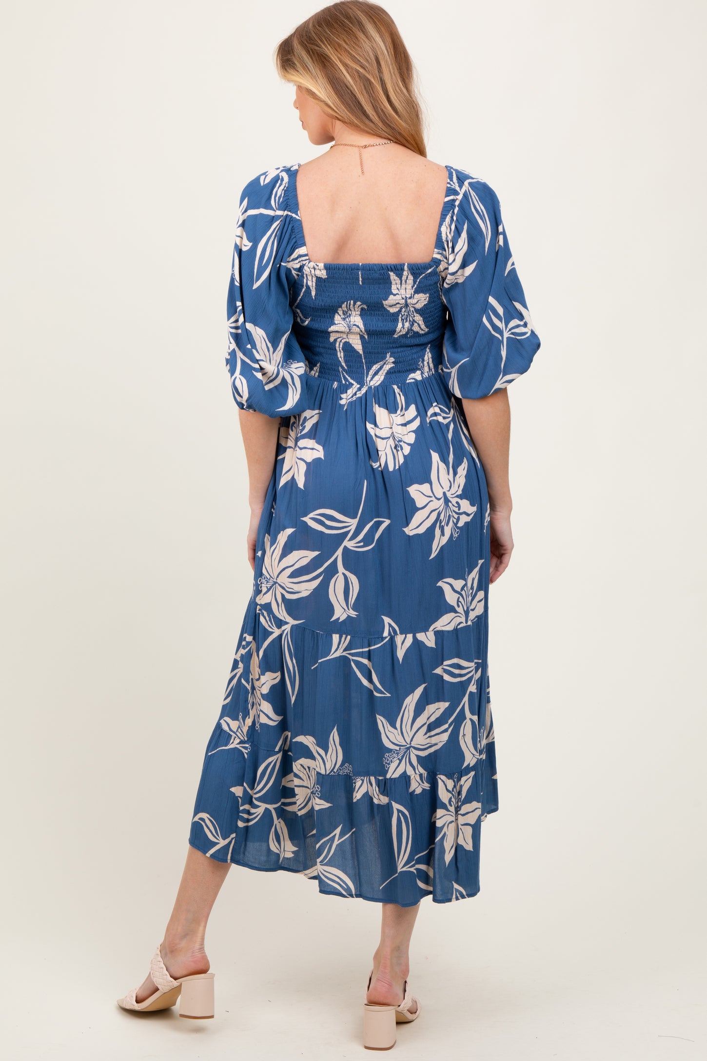 woman wearing a blue floral maternity dress with puff sleeves and a smocked bodice, showing her baby bump