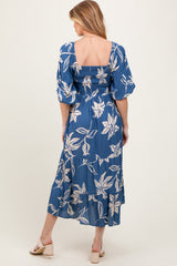 woman wearing a blue floral maternity dress with puff sleeves and a smocked bodice, showing her baby bump