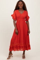 woman wearing a coral midi dress with ruffled sleeves and lace detailing, standing against a neutral background