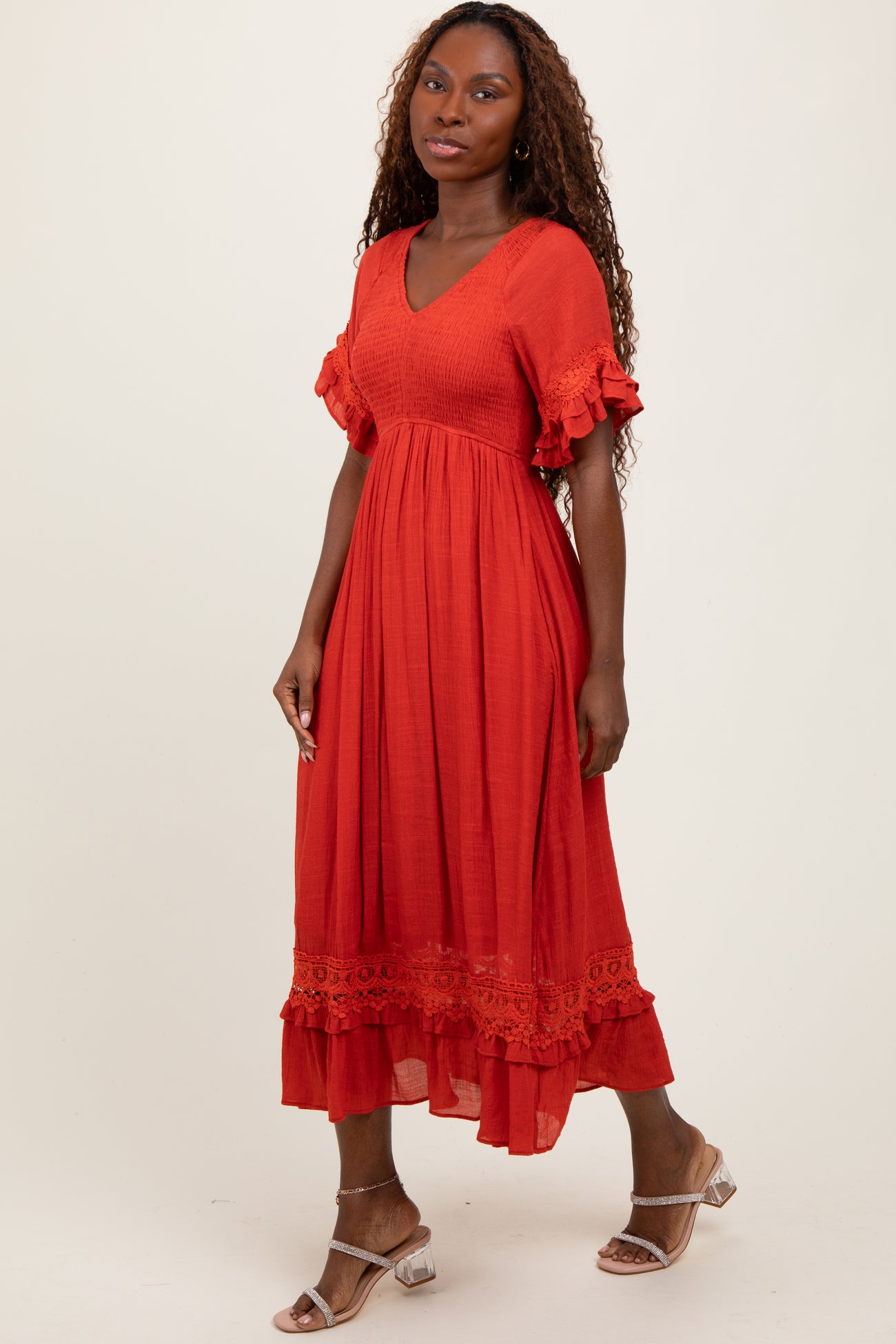 woman wearing an orange midi dress with short ruffled sleeves and lace trim details