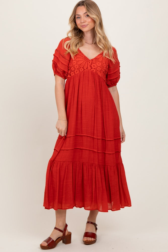 woman wearing a rust tiered maxi dress with short puff sleeves and lace detailing at the neckline