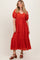 woman wearing a rust tiered maxi dress with short puff sleeves and lace detailing at the neckline