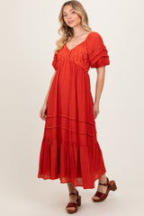 woman wearing a red tiered maxi dress with lace detailing and puff sleeves, styled with brown heeled sandals