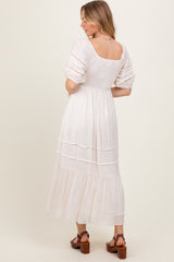 woman wearing a white tiered maxi dress with puff sleeves and a low back, seen from the back