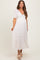 woman wearing a white maternity maxi dress with puff sleeves and lace details, showcasing her baby bump