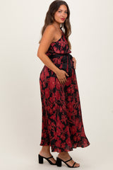 woman wearing a black and red floral maternity maxi dress with a tied waist and holding her baby bump