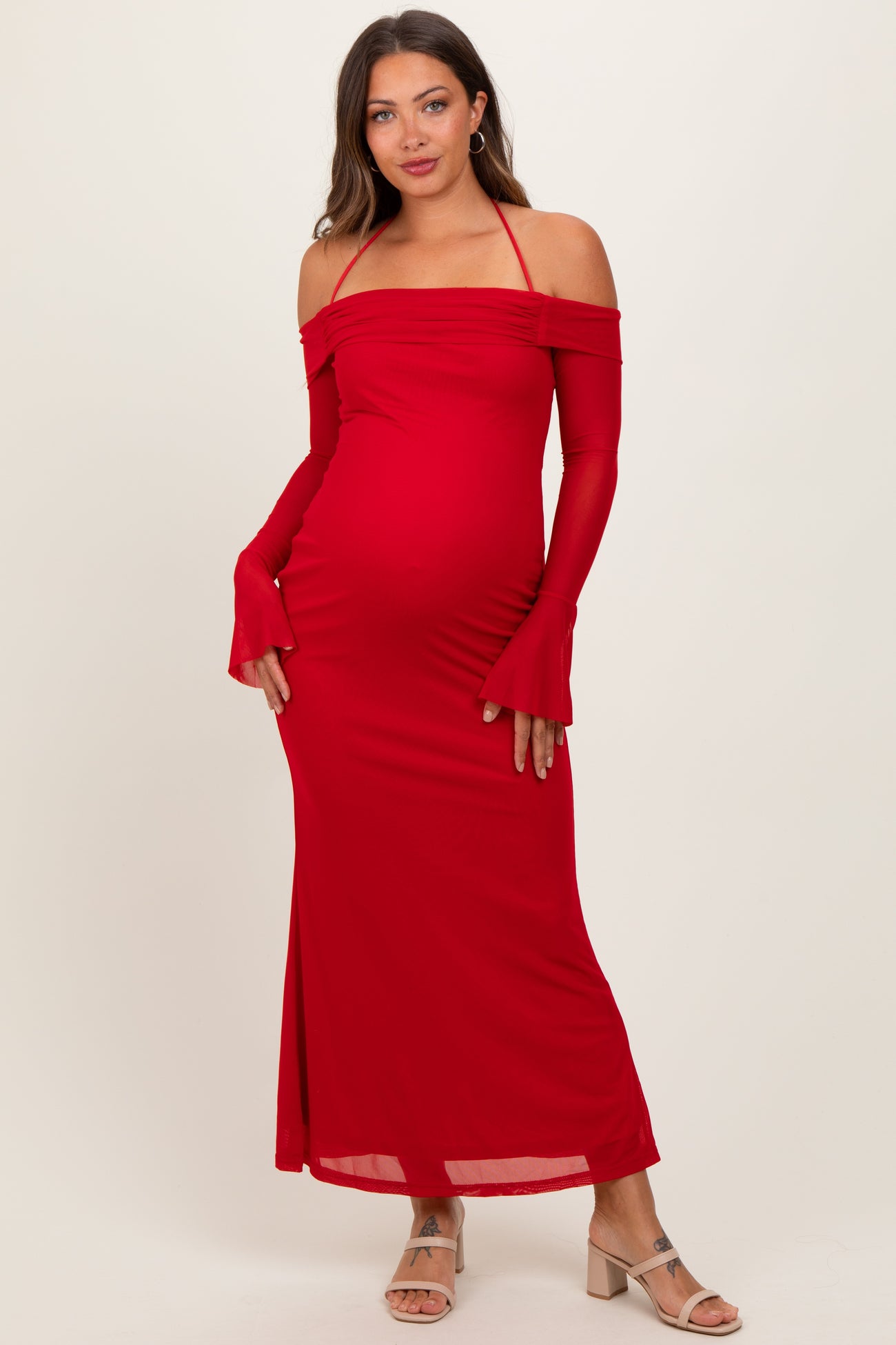 woman wearing a red off-the-shoulder maternity dress with long sleeves and a fitted silhouette, showing her baby bump