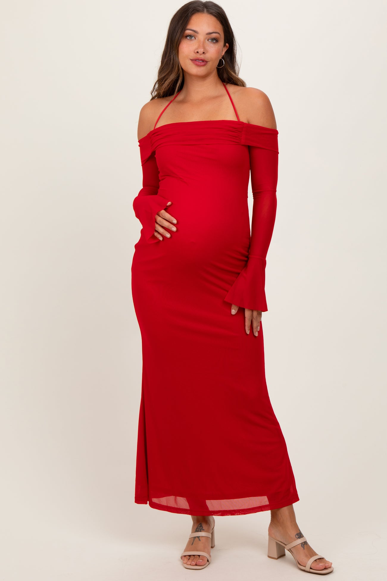 woman wearing a red off-the-shoulder maternity dress with long sleeves and a baby bump visible