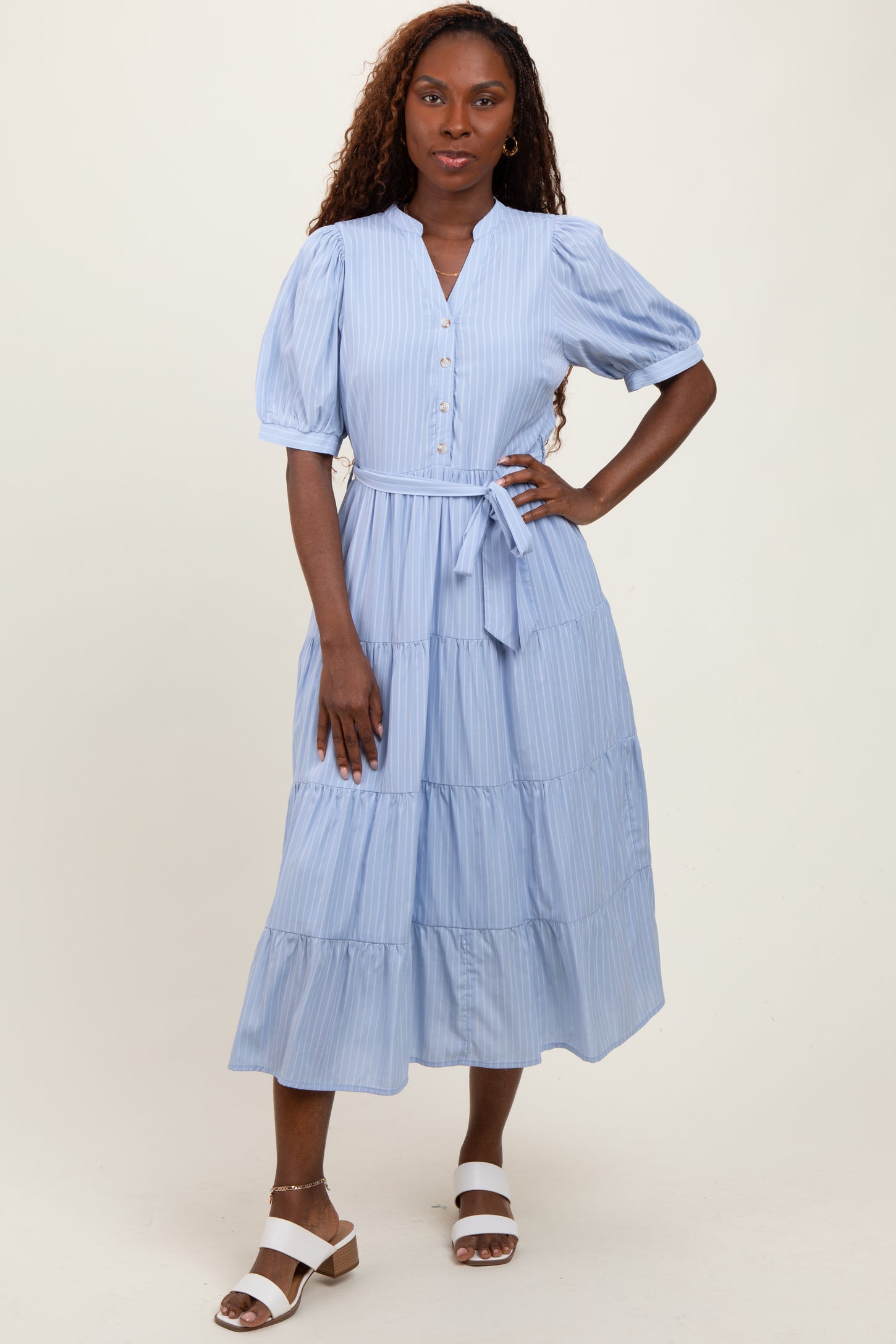 woman wearing a light blue tiered midi dress with puff sleeves and a tie waist detail