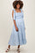 woman wearing a light blue maternity dress with floral print, smocked bodice, and tie straps, showing baby bump