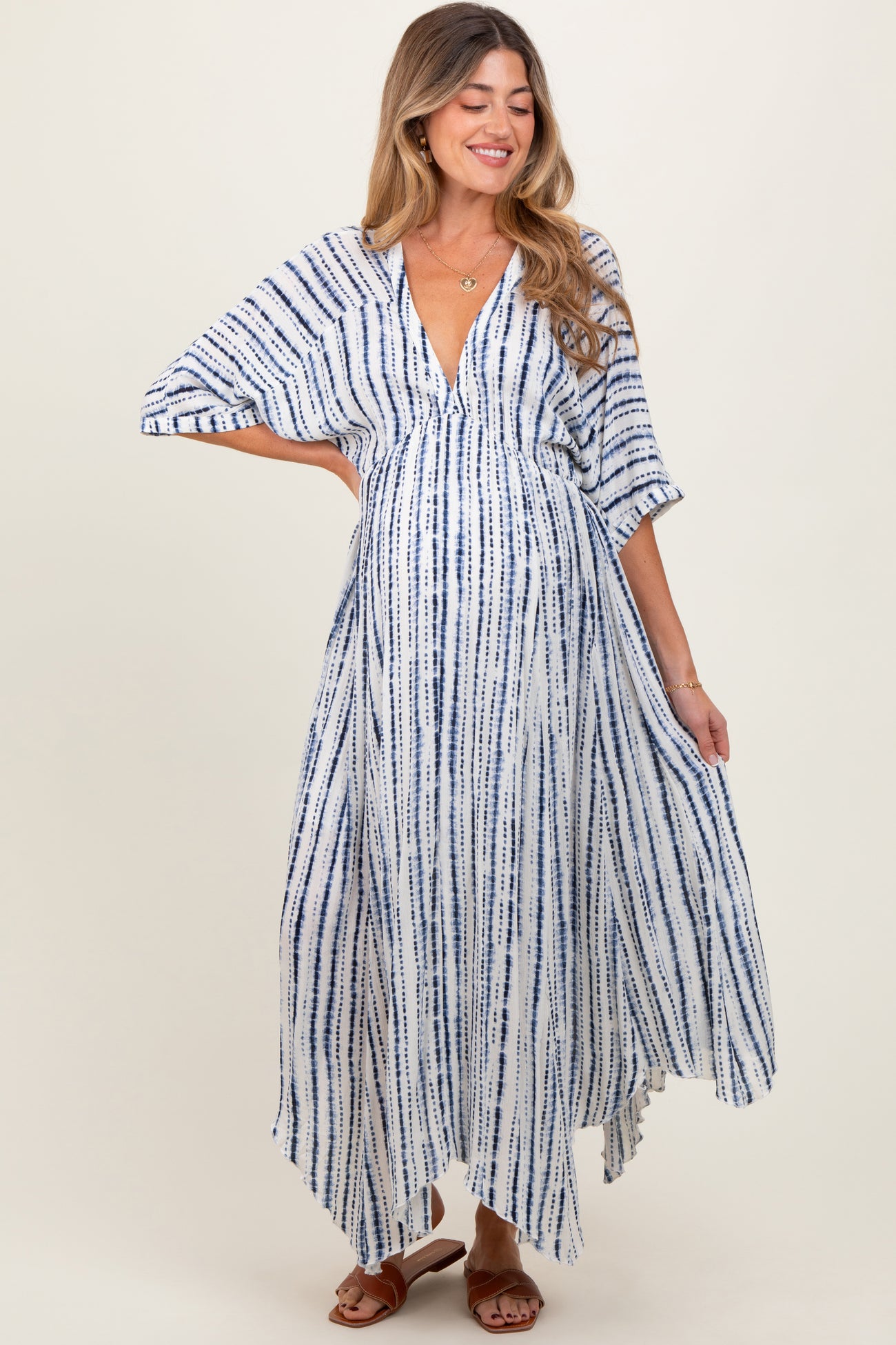 woman wearing a navy and white striped maternity maxi dress with a deep v-neck and flowing sleeves, showing her baby bump