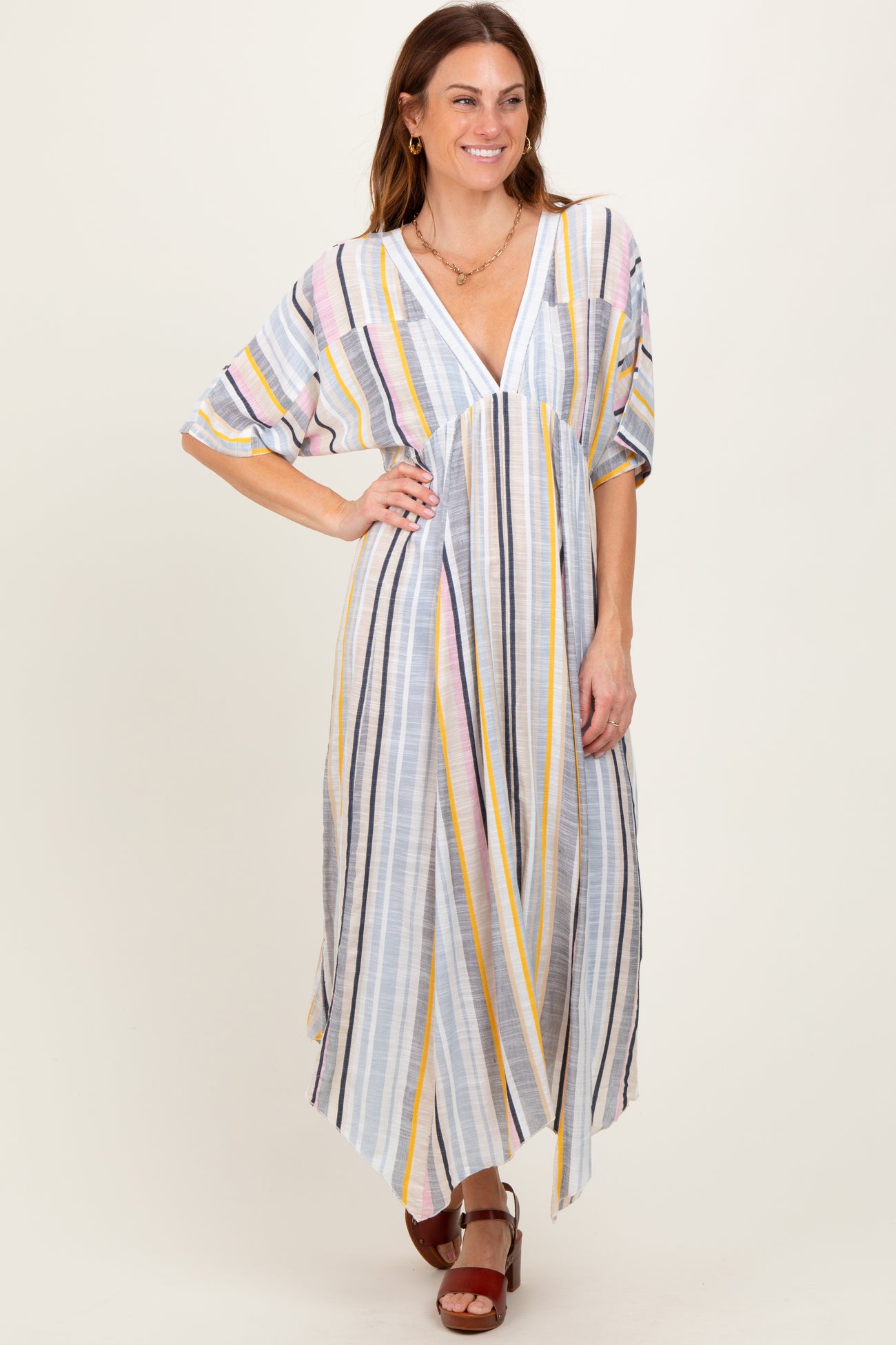 woman wearing a pastel striped maxi dress with a v-neck and wide sleeves