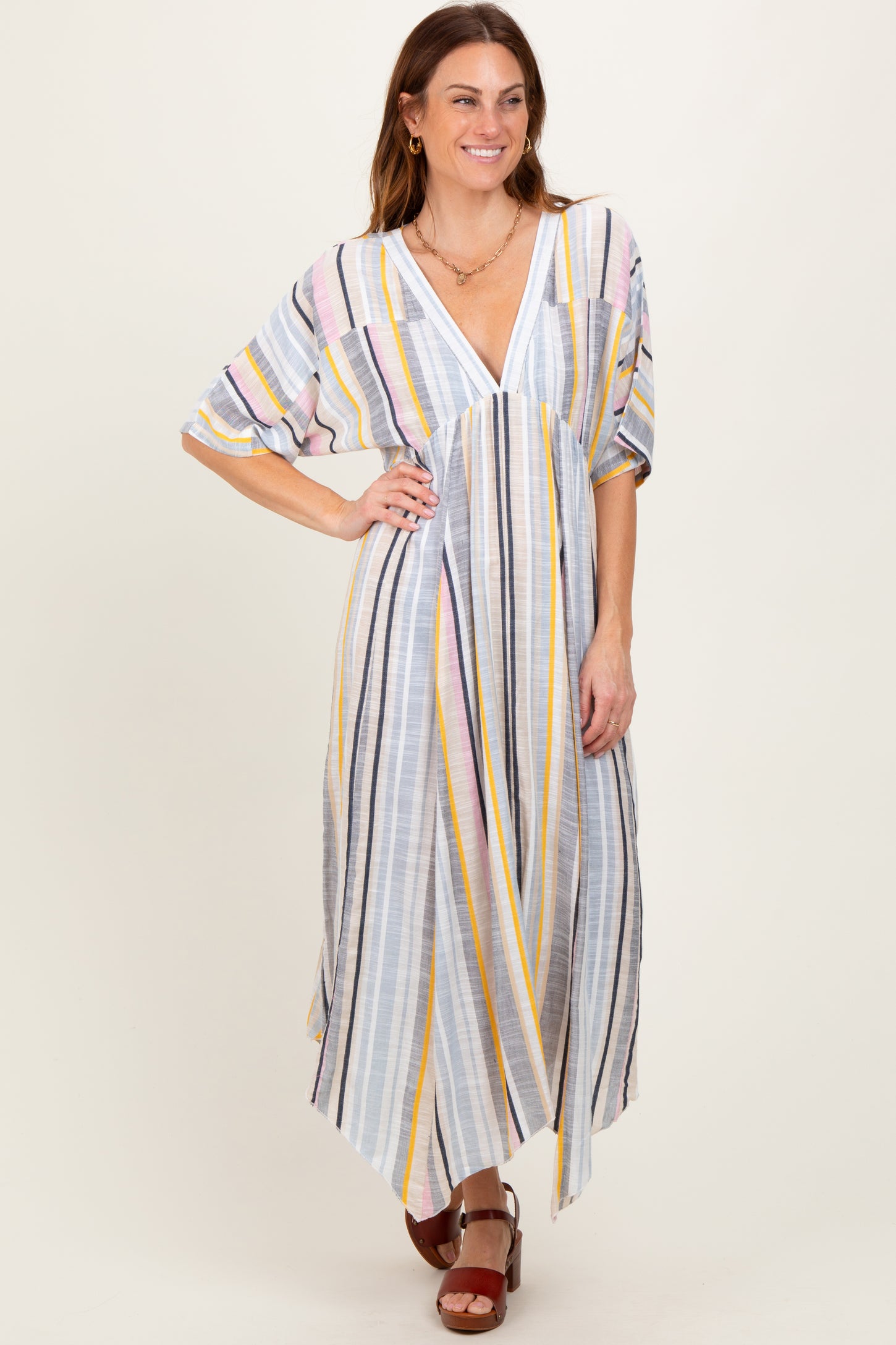 woman wearing a pastel striped maxi dress with a v-neck and wide sleeves