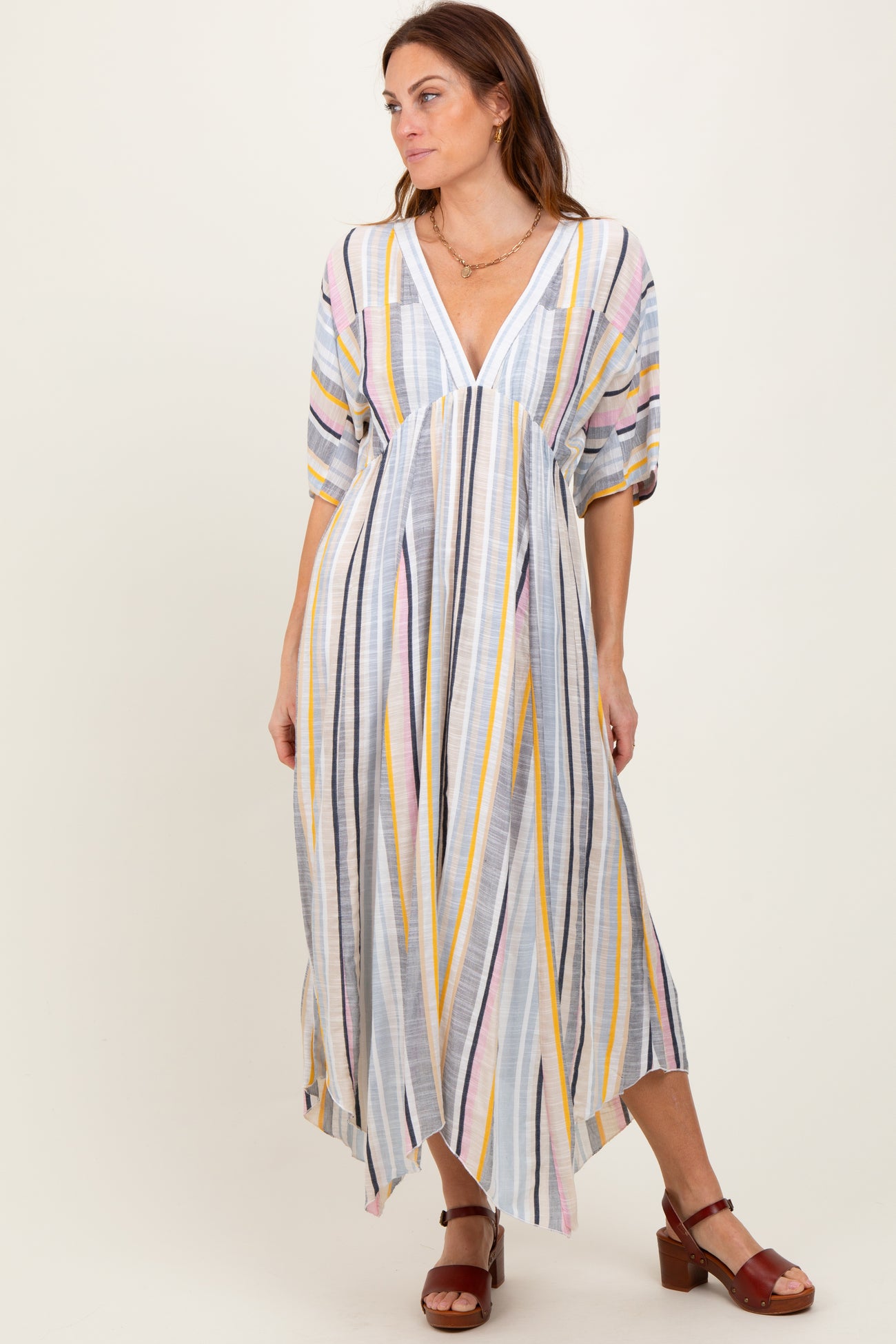 woman wearing a multi-colored striped maxi dress with short sleeves and a deep V-neckline