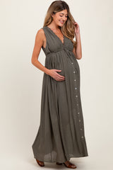 woman wearing an olive green sleeveless maternity maxi dress with a button detail and crinkle fabric, holding her baby bump
