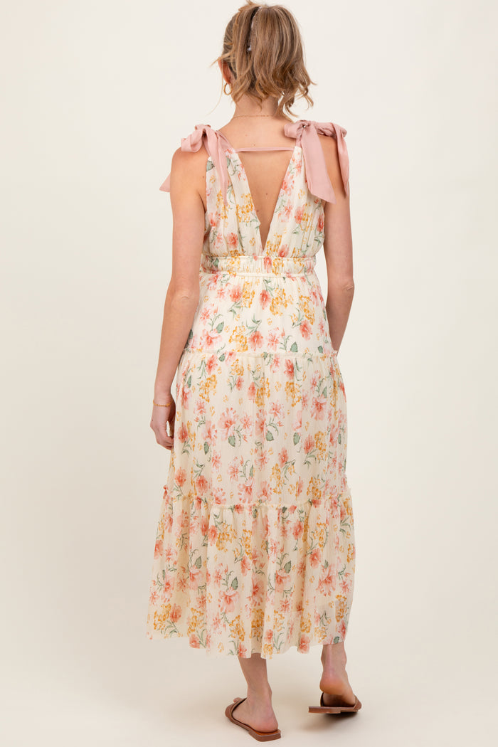 woman wearing a floral print maternity dress with tie shoulder straps and a backless design
