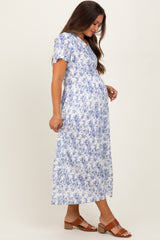 woman wearing a white floral maternity maxi dress with short sleeves and a visible baby bump
