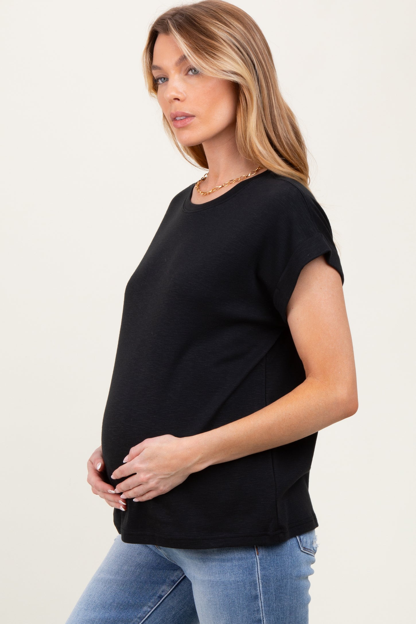 woman wearing a black short sleeve maternity top and holding her baby bump