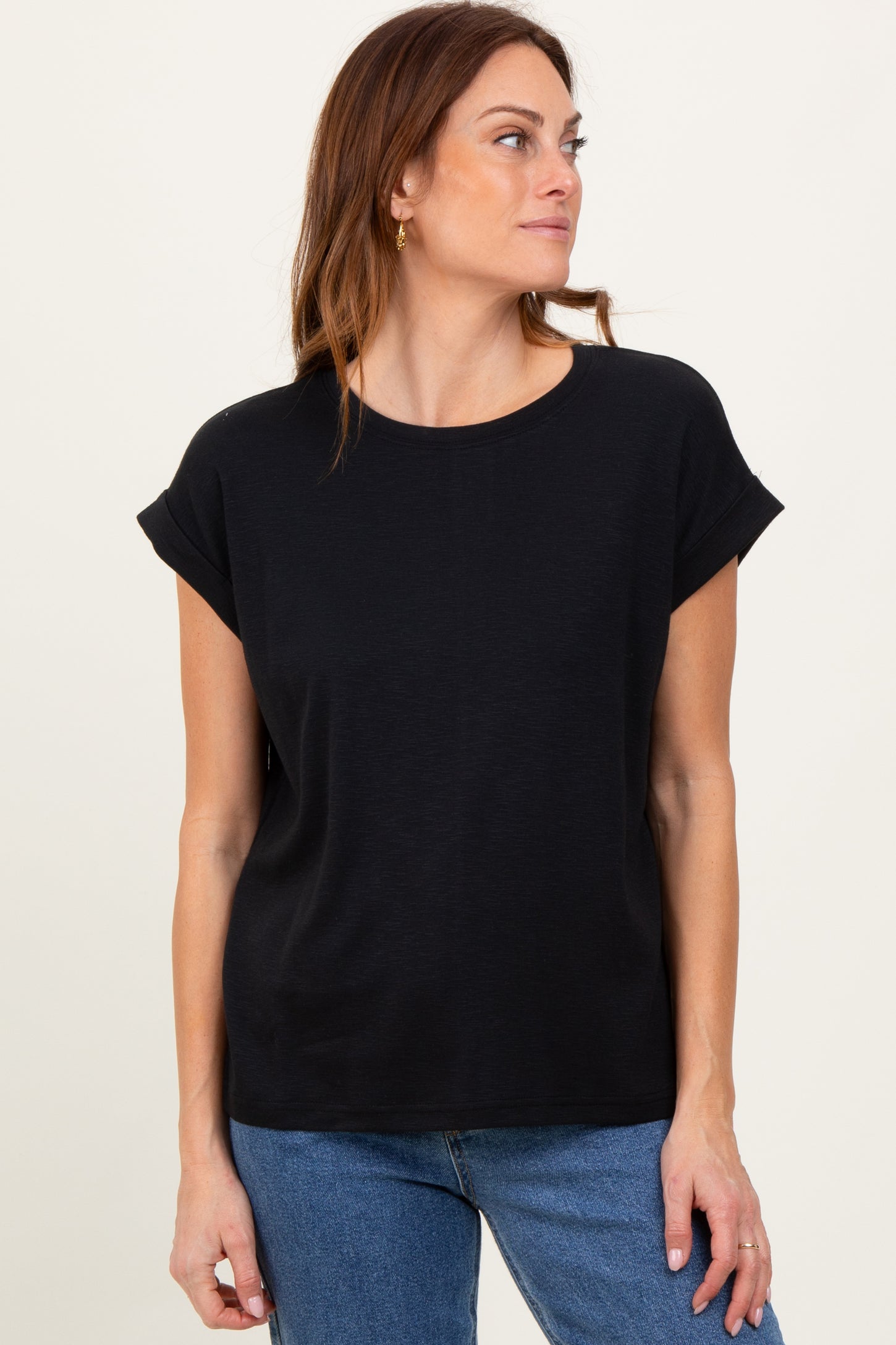 woman wearing a black short sleeve top with rolled cuffs and a relaxed fit paired with blue jeans