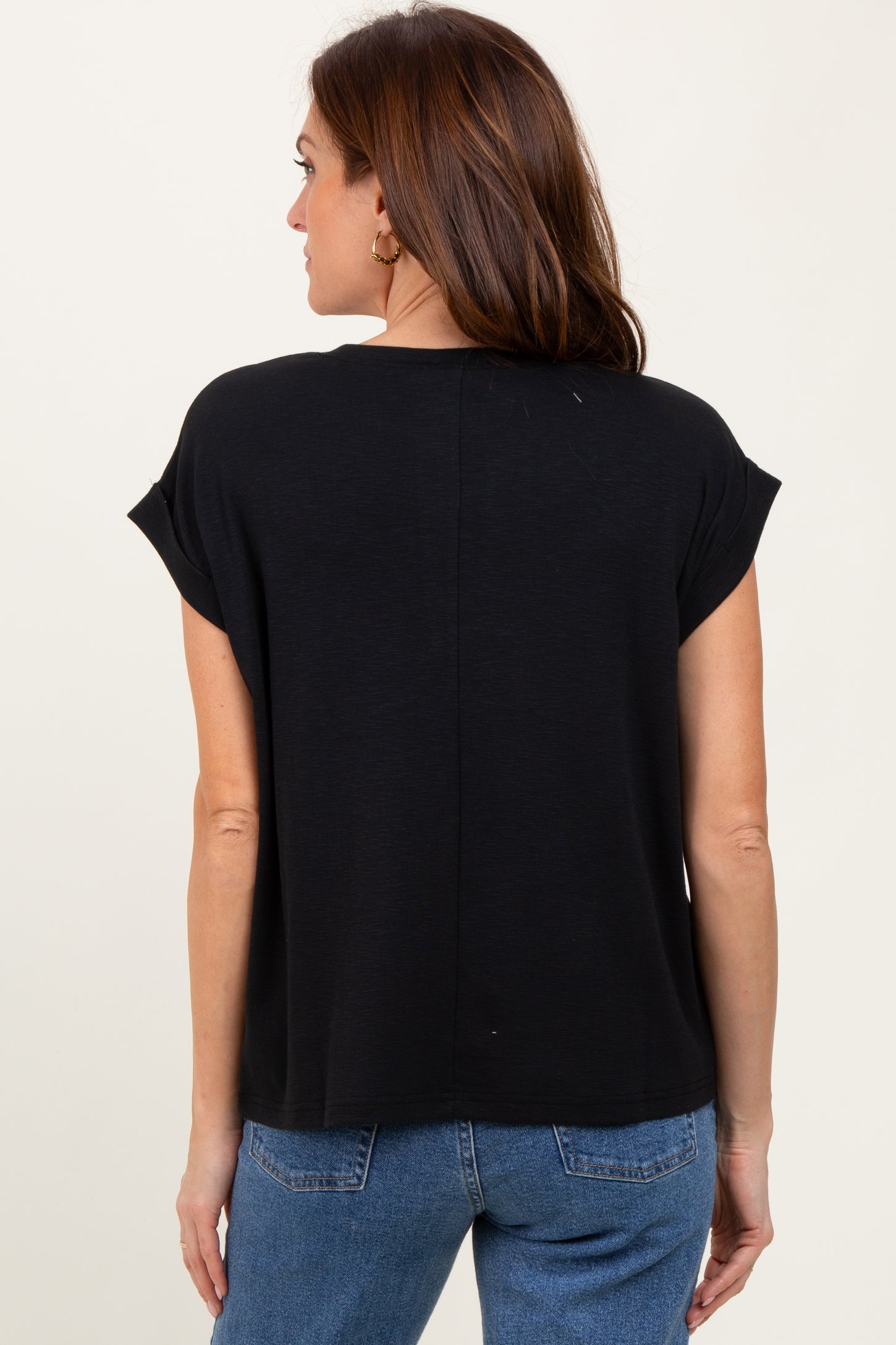 woman wearing a black short sleeve top, seen from the back, paired with blue jeans