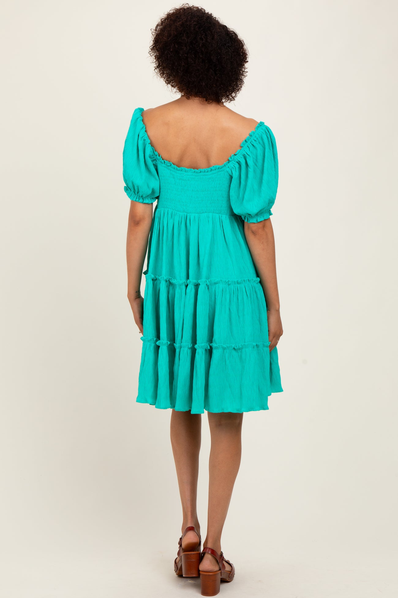 woman wearing a vibrant turquoise tiered dress with puff sleeves, shown from the back