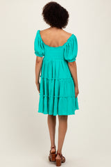 woman wearing a vibrant turquoise tiered dress with puff sleeves, shown from the back