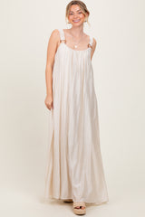 woman wearing a light beige maxi dress with adjustable straps and side slits, smiling at the camera