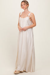 woman wearing a light beige maxi dress with adjustable straps and a relaxed fit