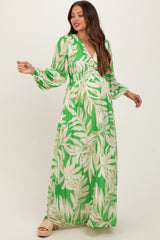 woman wearing a green maternity maxi dress with leaf print and long sleeves, showcasing her baby bump