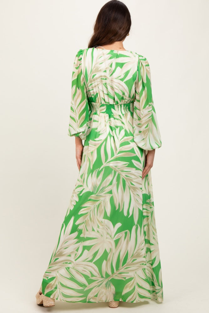 woman wearing a green maxi dress with a floral pattern and smocked waist, viewed from the back