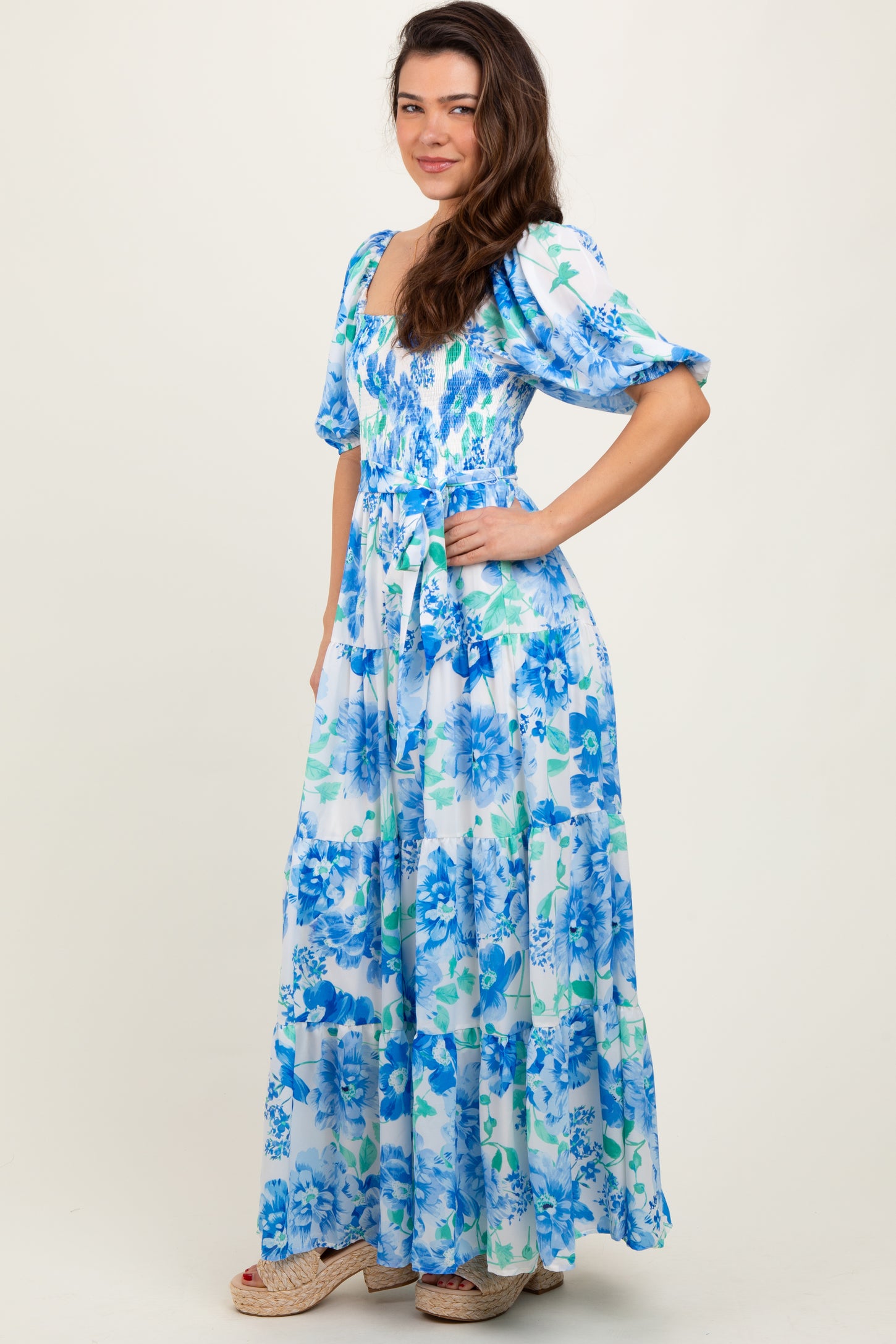 woman wearing a floral blue and white maxi dress with puff sleeves and a tiered skirt