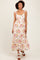 woman wearing a floral maxi dress with ruffled straps and a fitted waist, standing against a light background