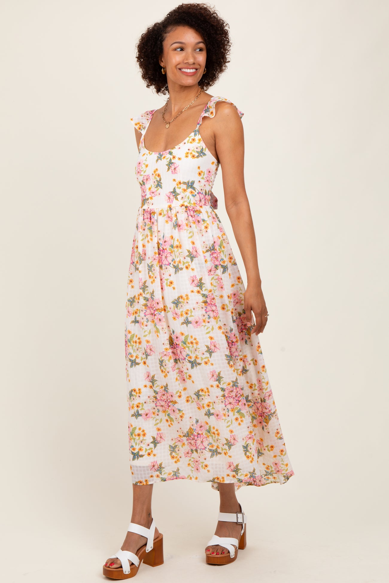 woman wearing a white floral maxi dress with ruffled straps and a fitted bodice