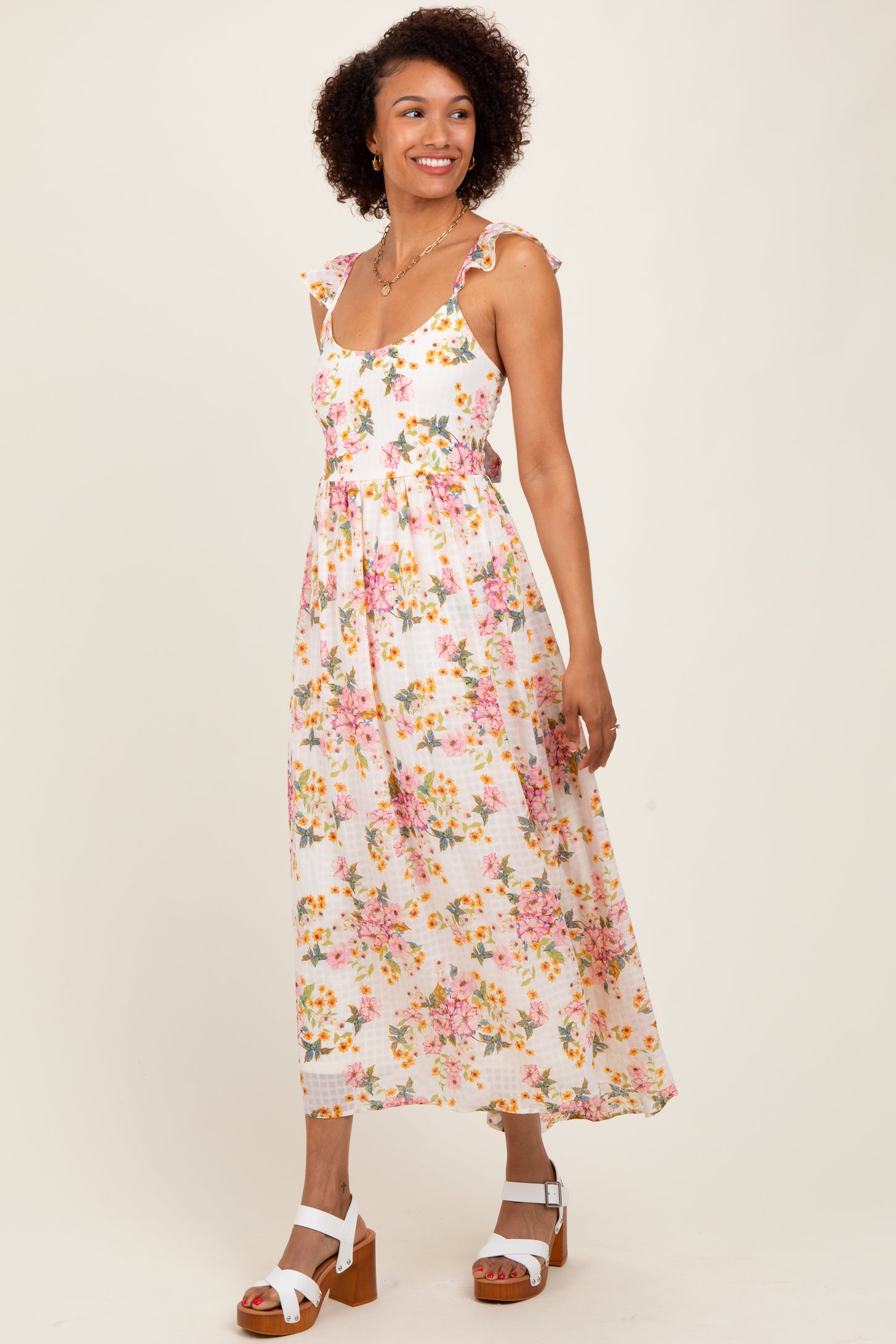 woman wearing a white floral maxi dress with ruffled straps and a fitted bodice