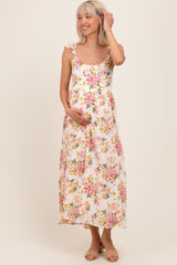 woman wearing a white floral maternity maxi dress with ruffled straps and holding her baby bump