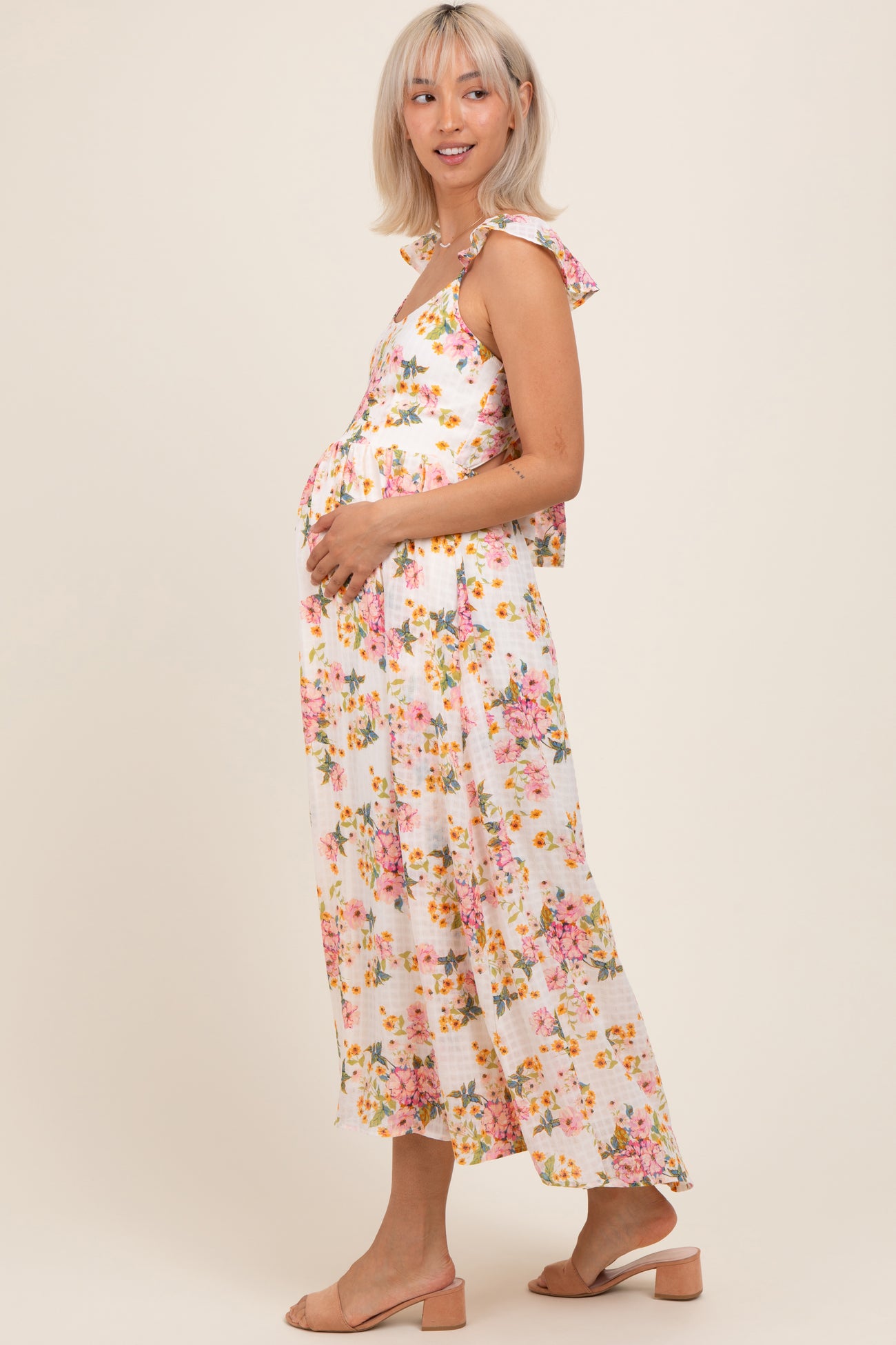 woman wearing a floral maternity maxi dress and holding her baby bump